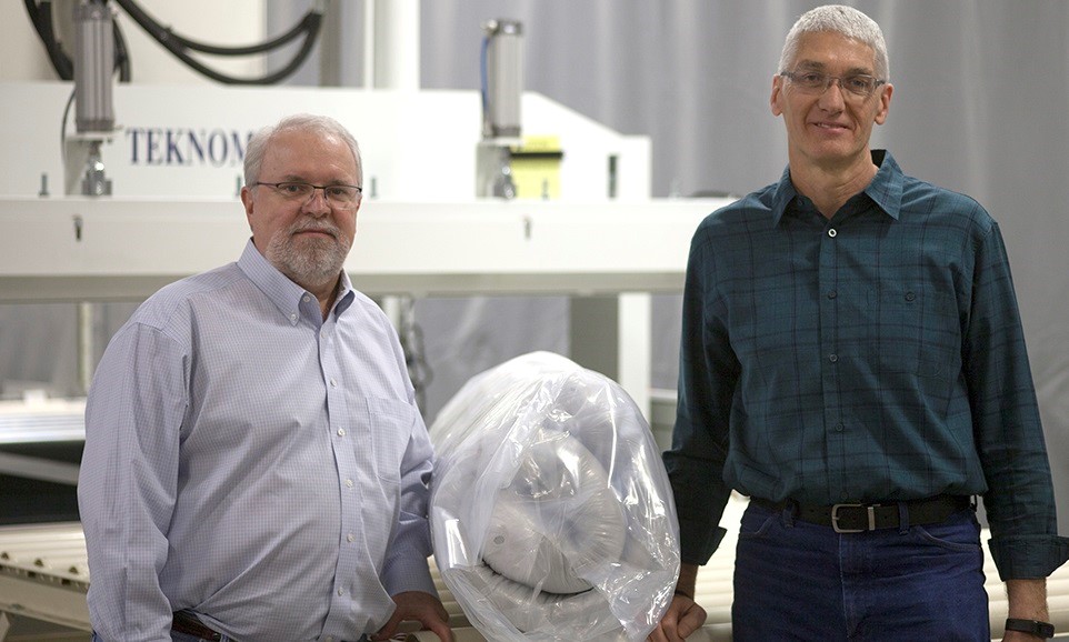 Tony Garrett, President of GSG, and Terry Myers, Director of Engineering, with a Teknomac machine and roll-pack mattress.